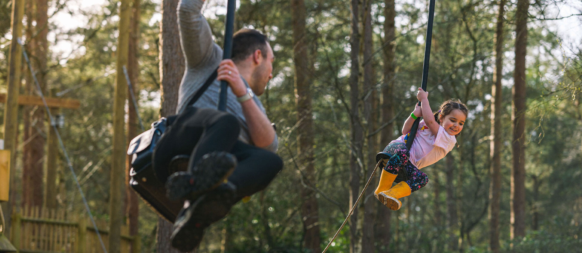 A father and child whizz along the zip wires at BeWILDerwood