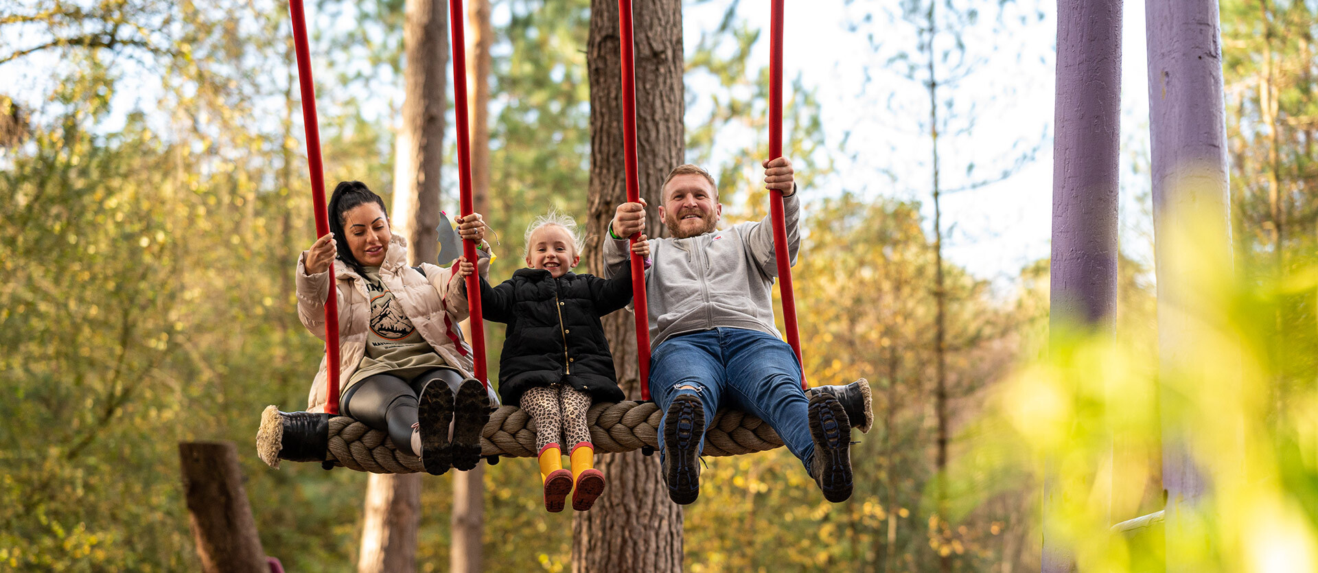A family play together on a swing during Autumn at BeWILDerwood